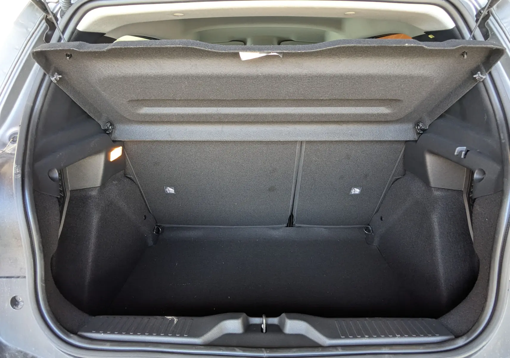 Coffre ouvert de la Citroën E-C3 113 MAX gris Mercury, vue arrière montrant l’espace de rangement vide et l’éclairage intérieur.