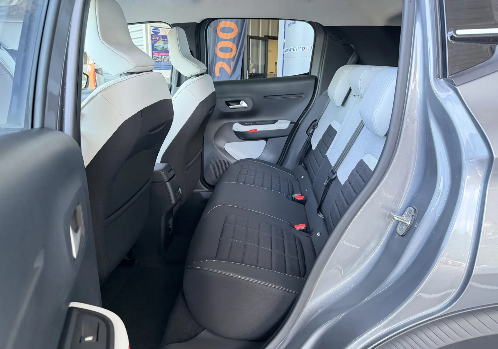 Vue intérieure arrière côté droit de la Citroën E-C3 113 MAX gris Mercury, avec sellerie tissu noir et clair et vitres surteintées.