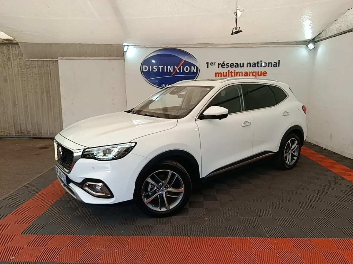 Vue 3/4 avant droit d’un SUV MG EHS blanc, avec jantes alliage et calandre chromée dans un showroom.