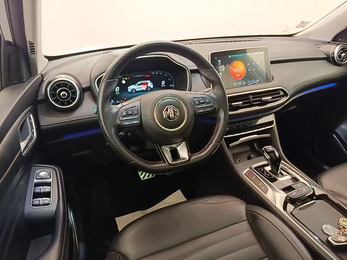 Vue intérieure avant du tableau de bord et volant cuir noir du MG Motor EHS 1.5T PHEV avec écran tactile central.