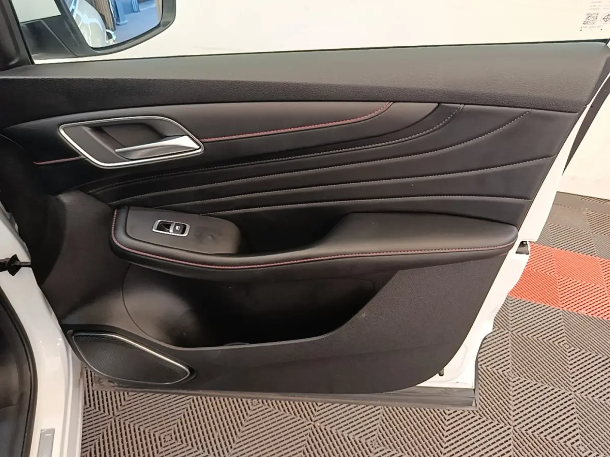 Porte intérieure côté gauche de MG Motor EHS blanc, avec garniture noire et surpiqûres rouges visibles.