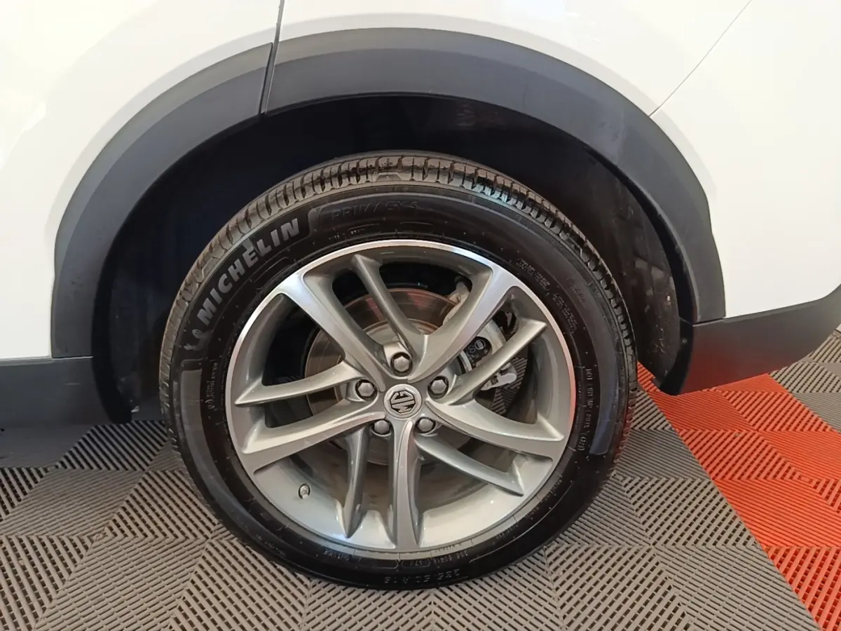 Gros plan sur la roue avant droite d’un MG MOTOR EHS blanc, avec jante alliage et pneu Michelin visible.