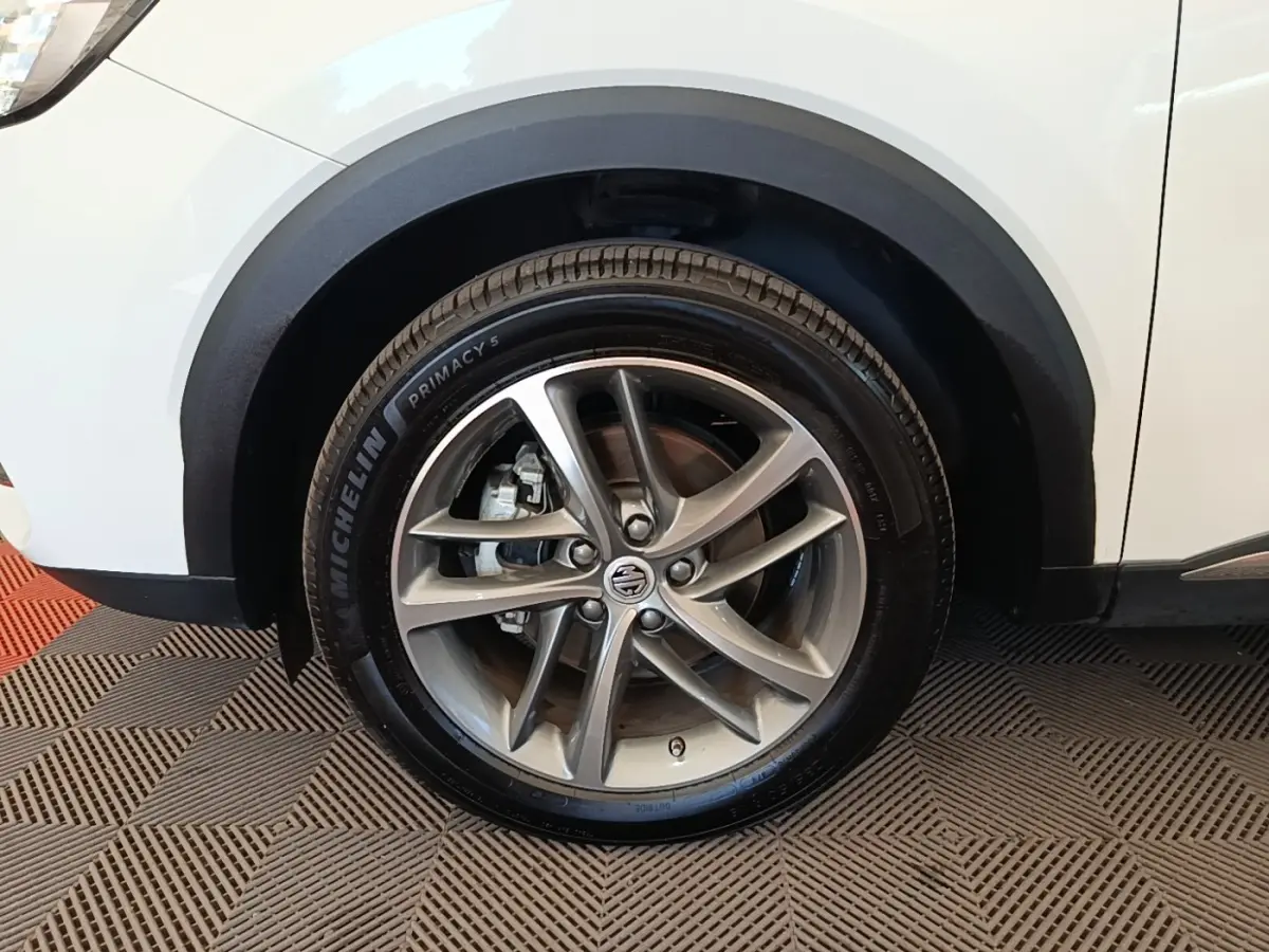 Gros plan sur la roue avant gauche en alliage gris d’un MG Motor EHS blanc avec passage de roue noir.