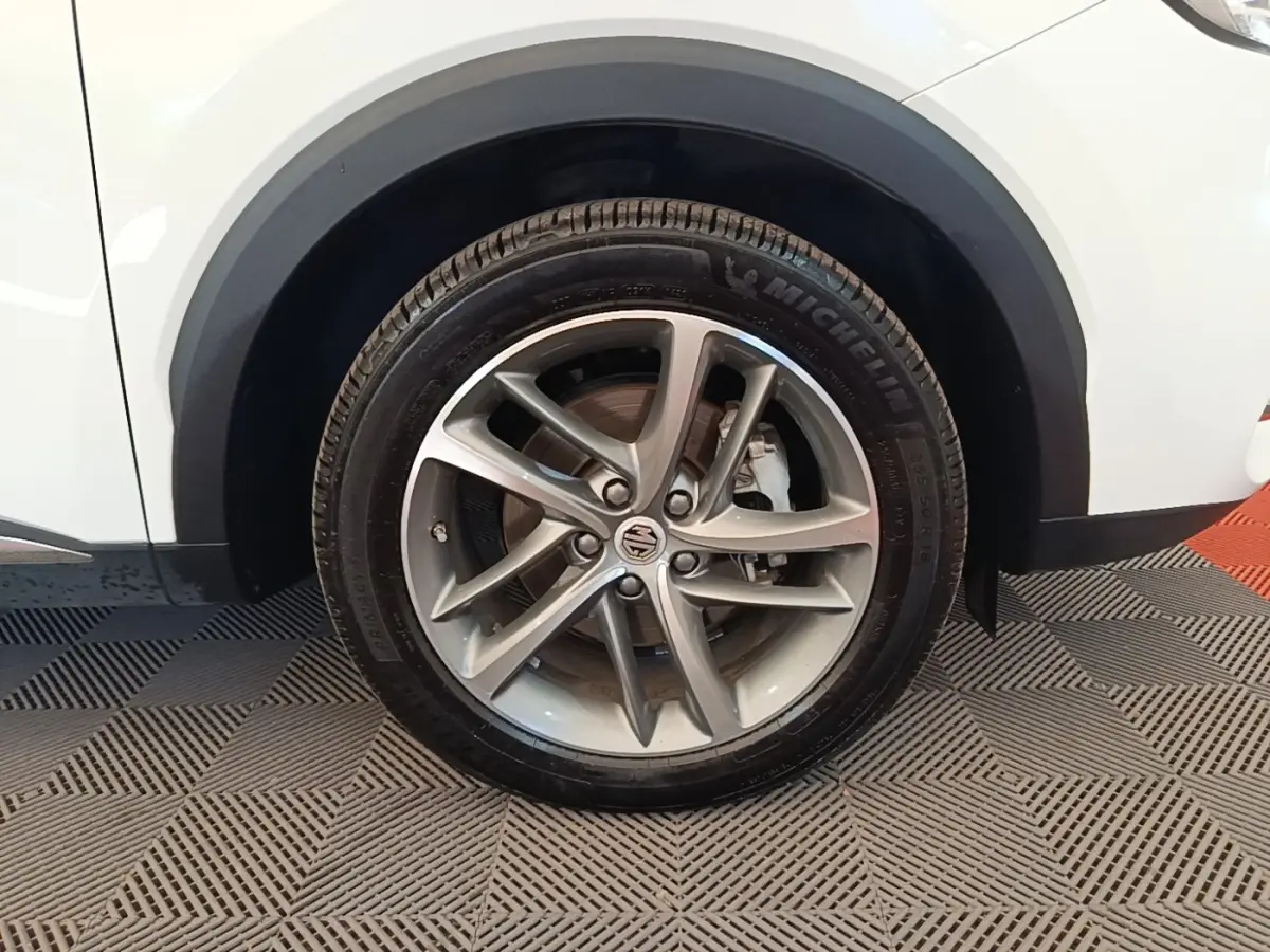 Gros plan sur la roue avant droite d’un MG Motor EHS blanc, jante alliage argentée à 5 doubles branches.