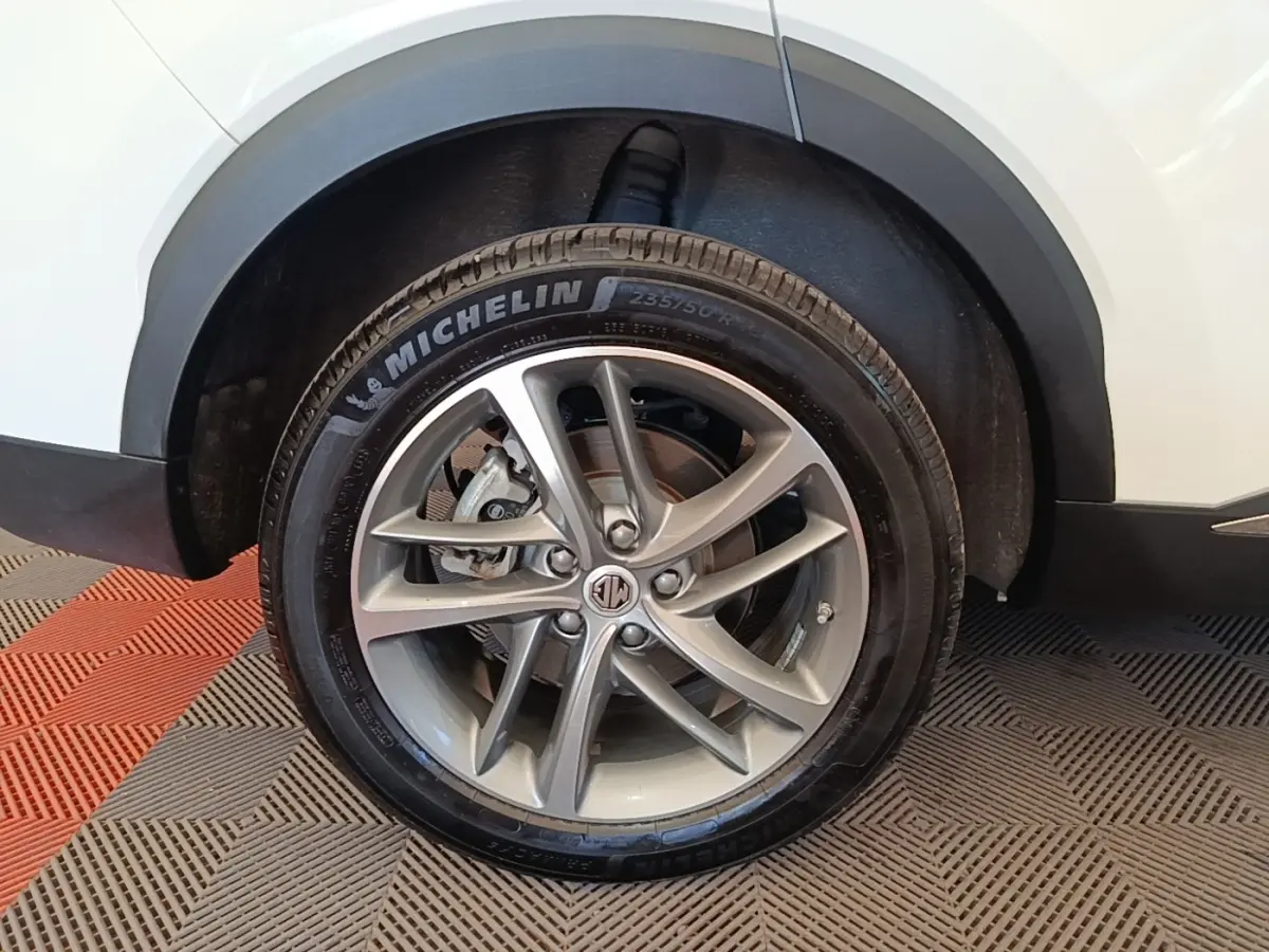 Gros plan sur la roue avant droite du MG MOTOR EHS blanc, avec jante alliage et pneu Michelin visible.