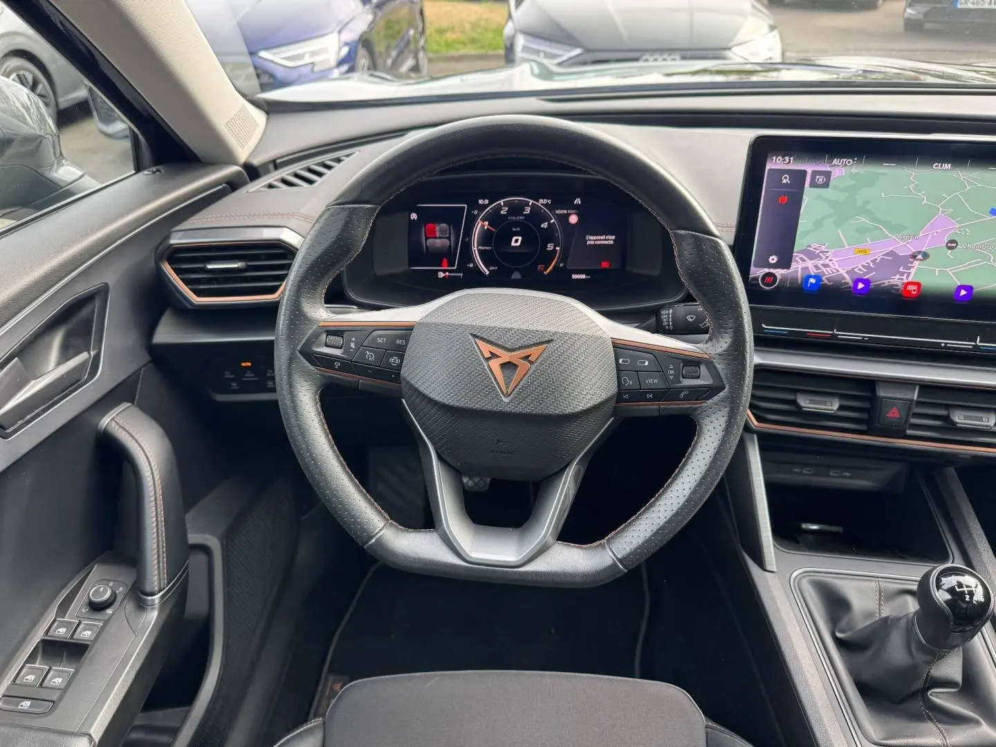 Vue intérieure centrée sur le volant sport noir et cuivre du CUPRA Formentor 2023 avec tableau de bord numérique et écran tactile GPS.