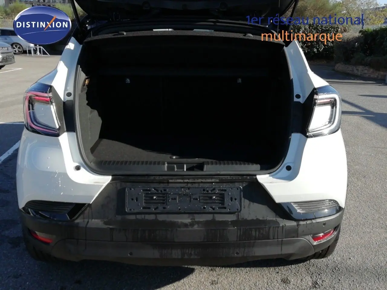 Vue arrière d’un Renault Captur blanc nacré avec coffre ouvert et toit noir visible, en extérieur sur parking.