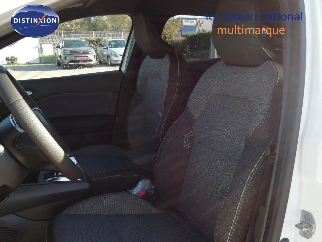 Vue intérieure côté conducteur du Renault Captur blanc nacré avec sièges tissu gris foncé et volant cuir.