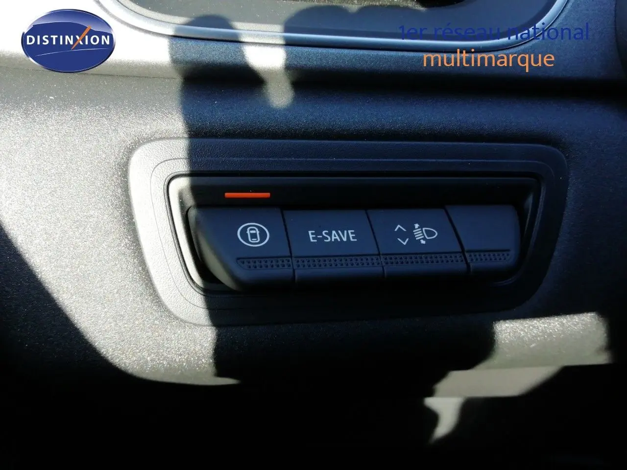 Gros plan sur les boutons de commande E-SAVE et réglage des phares du tableau de bord du Renault Captur blanc nacré 2026.