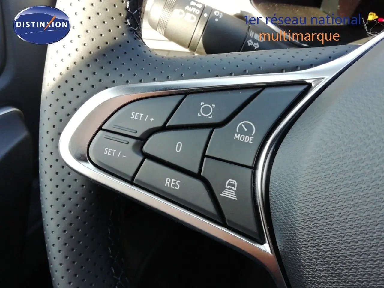 Gros plan sur les commandes au volant perforé du Renault Captur 2026, version hybride, avec finition noire et argentée.