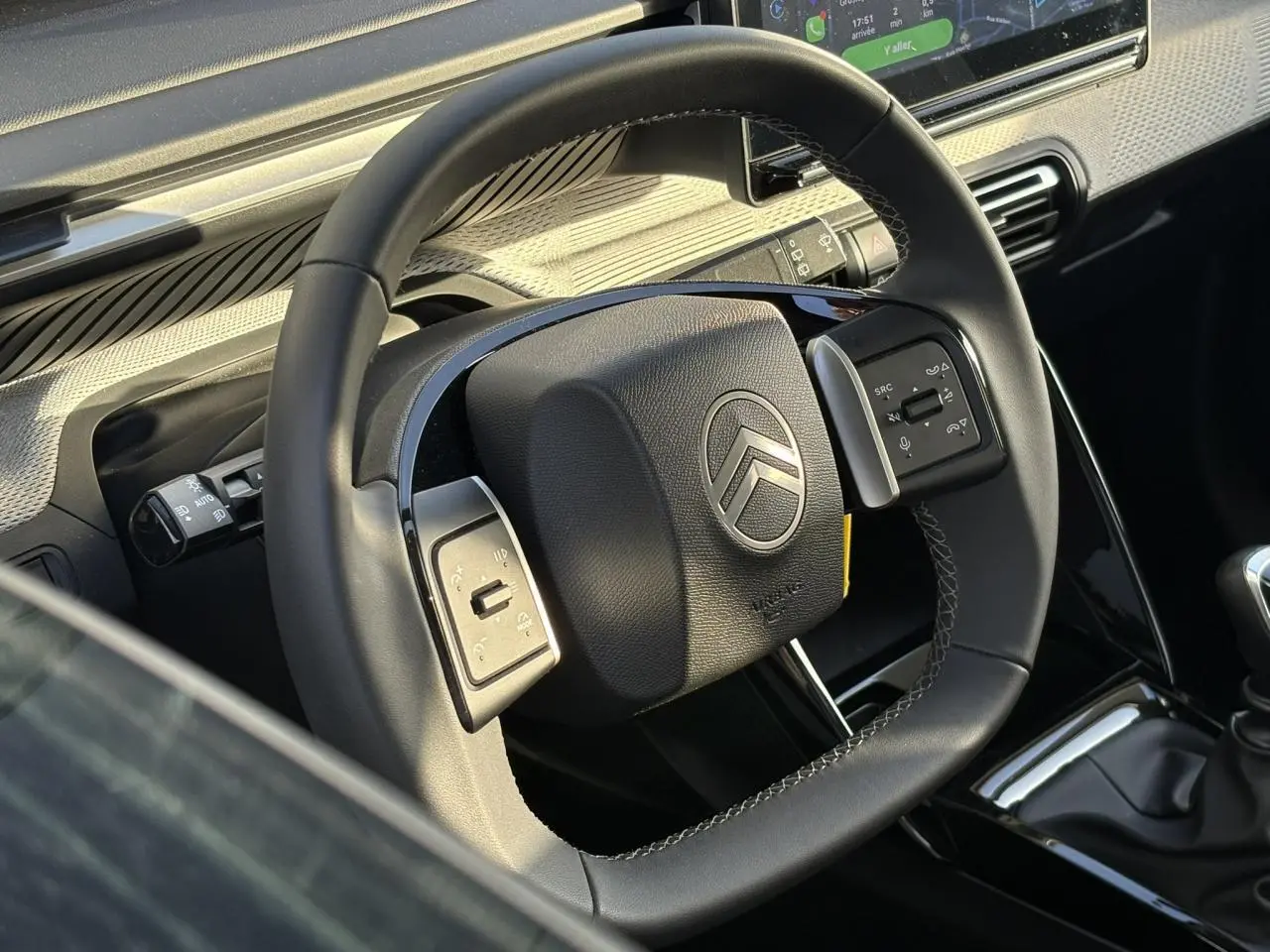 Gros plan sur le volant noir de la Citroën C3 2025 avec commandes intégrées et tableau de bord en arrière-plan.