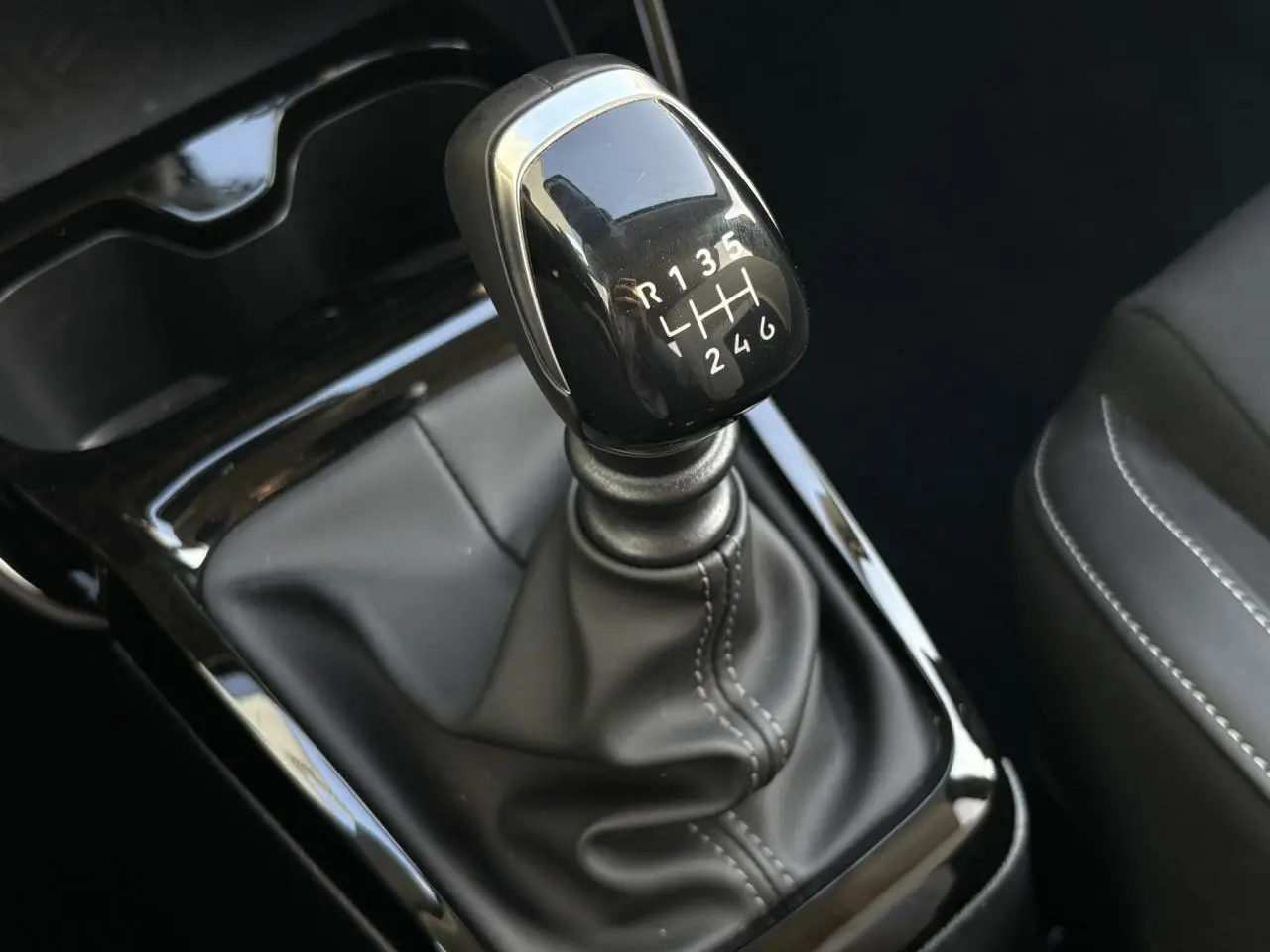 Gros plan sur le levier de vitesses manuel noir brillant de la Citroën C3 Turbo 100 Max, intérieur en cuir noir.