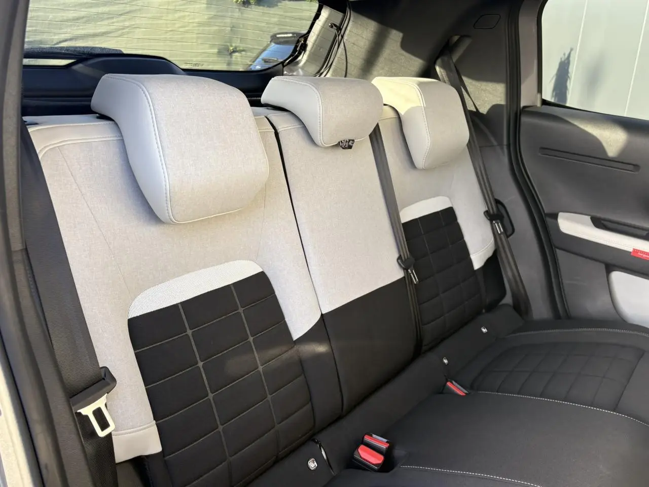 Vue intérieure des sièges arrière bi-coloris beige et noir de la Citroën C3 Turbo 100 Max, avec appuie-têtes et ceintures visibles.