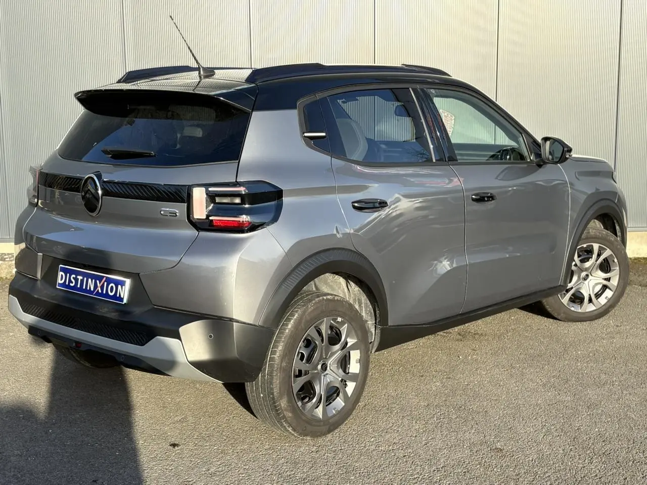 Vue 3/4 arrière droite d'une Citroën C3 2025 gris Mercury avec toit noir et feux arrière LED 3D.