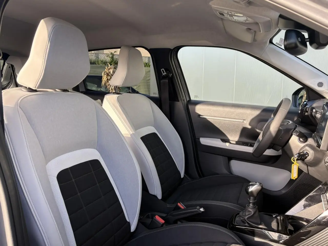 Vue intérieure côté droit montrant les sièges avant bicolores gris clair et noir de la Citroën C3 Turbo 100 Max 2025.