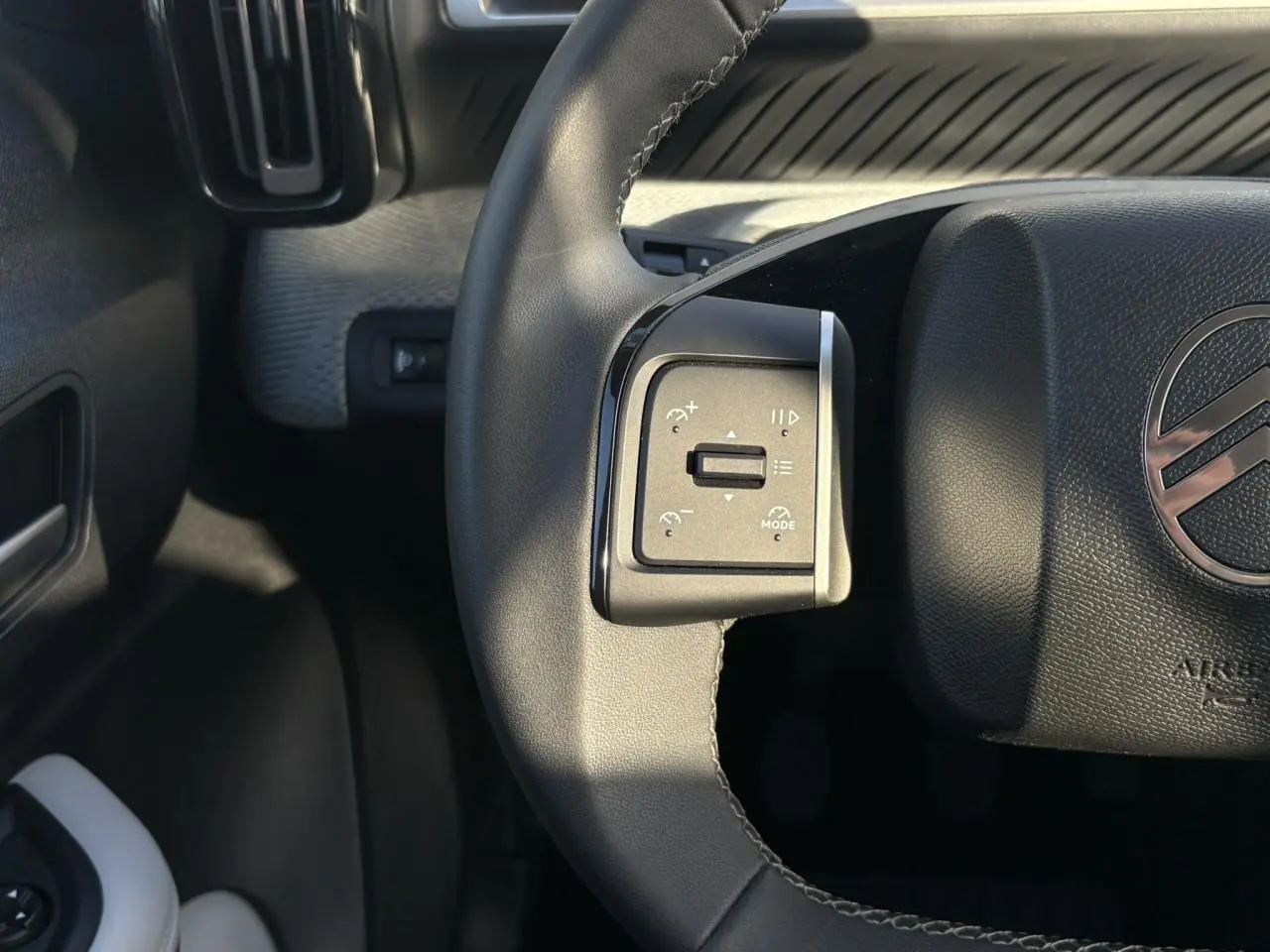 Gros plan sur la commande gauche du volant noir de la Citroën C3 Turbo 100 Max, avec logo Citroën visible.