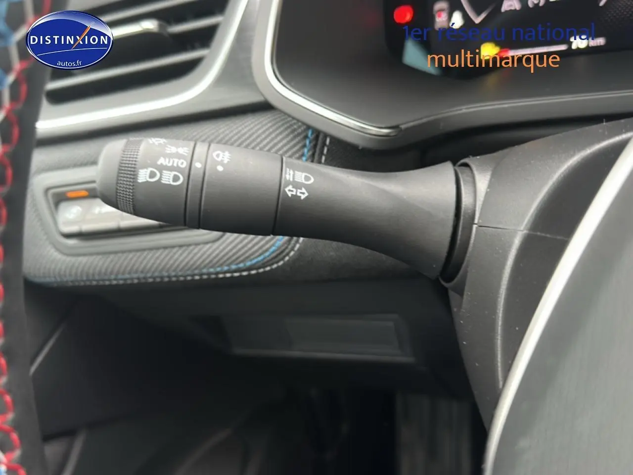 Détail du commodo d'éclairage à gauche du volant dans l'habitacle du Renault Captur bleu iron t/noir 2025 esprit alpine.