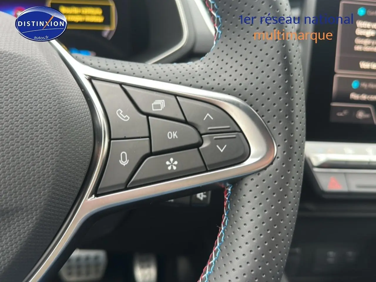 Gros plan sur les commandes multifonctions du volant cuir perforé du Renault Captur 1.8 e-tech hybride bleu iron t/noir.