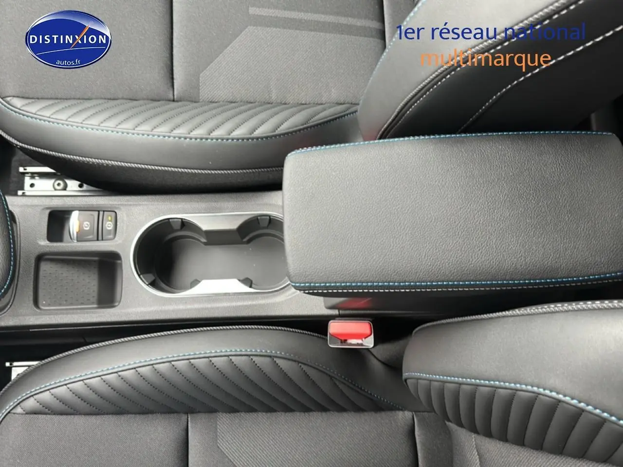 Gros plan sur l'accoudoir central noir avec surpiqûres bleues et porte-gobelets du Renault Captur 2025 intérieur.