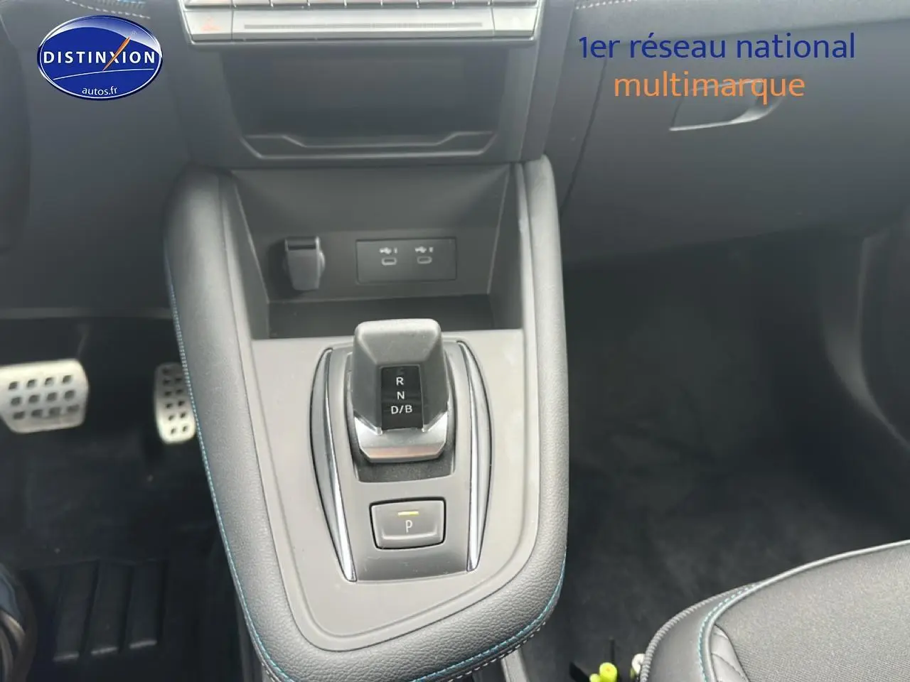 Vue plongeante sur la console centrale du Renault Captur 2025 hybride, avec levier de vitesse et surpiqûres bleues.