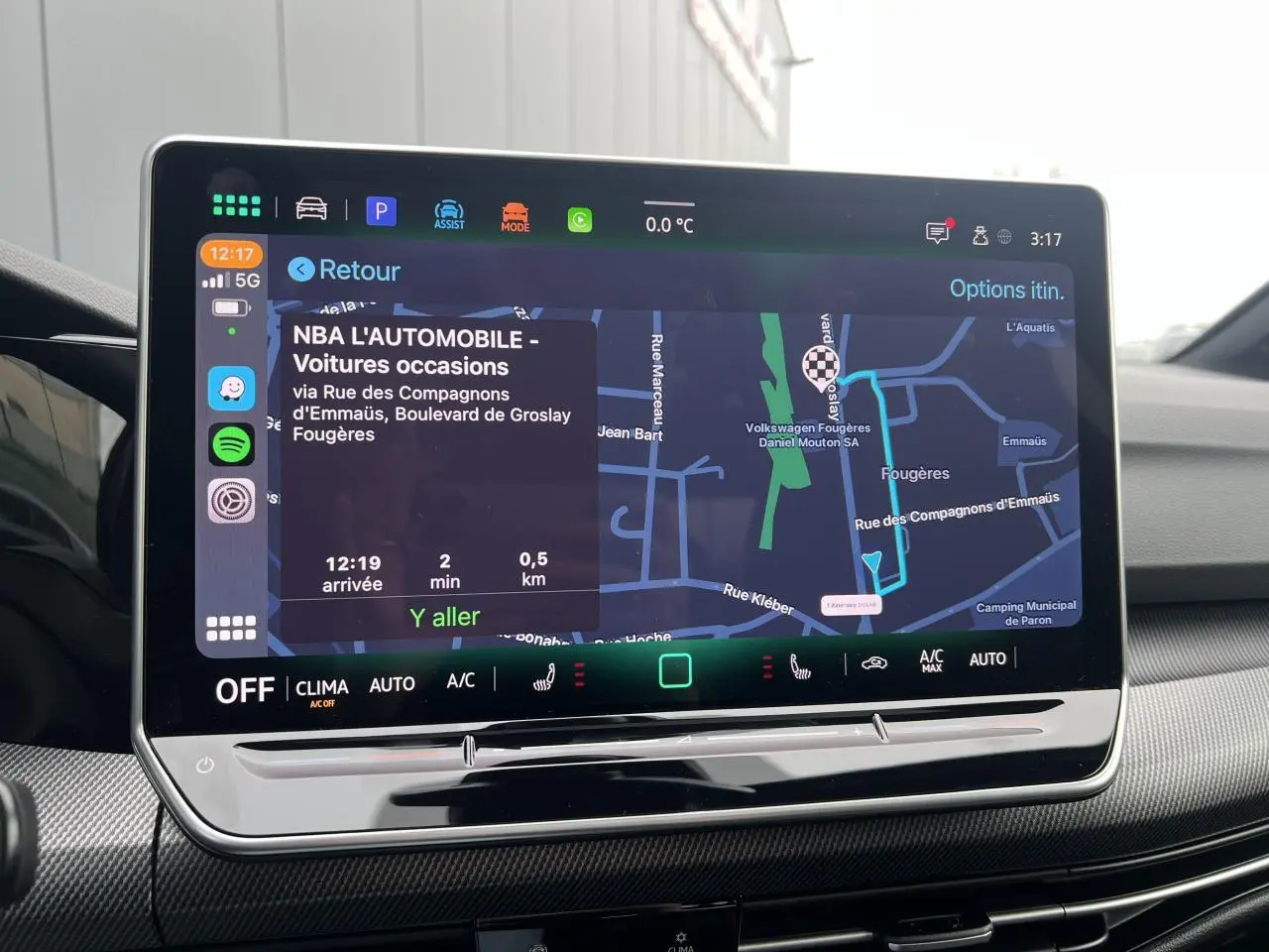 Écran tactile central de la Volkswagen Golf VIII noir, affichant la navigation avec carte et options climatisation.