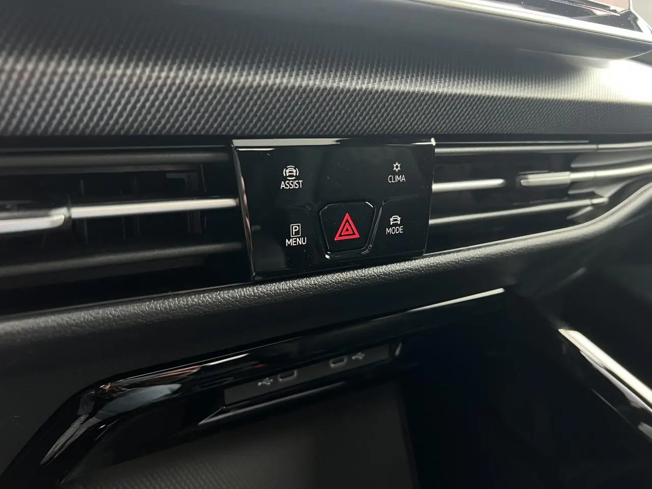 Détail du tableau de bord noir de la Volkswagen Golf VIII R-Line, avec commandes d'assistance et climatisation.