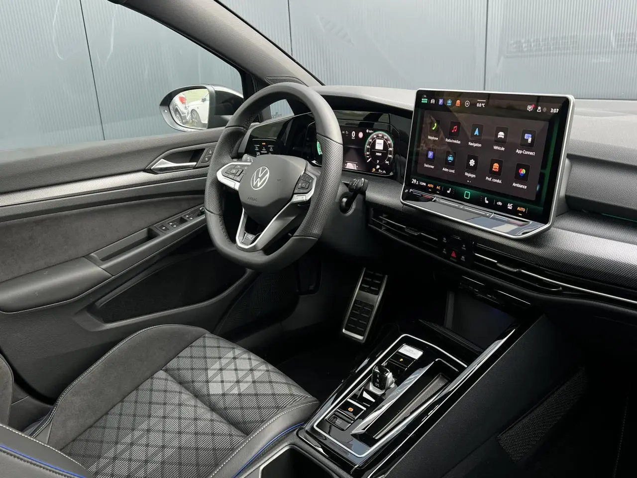 Vue intérieure côté conducteur de la Volkswagen Golf VIII R-Line avec tableau de bord numérique et écran tactile central.