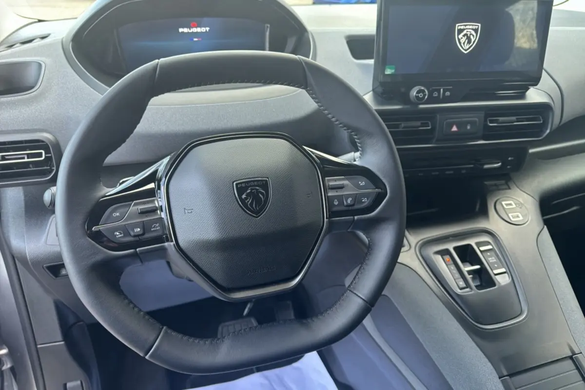 Vue intérieure centrée sur le volant cuir multifonctions et l’écran tactile du Peugeot Rifter gris Artense 2026.
