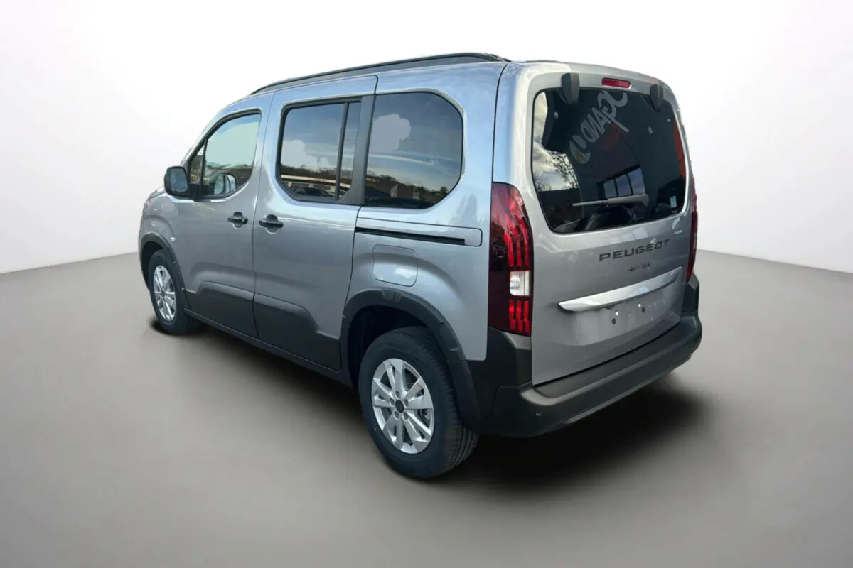 Vue 3/4 arrière droite d’un Peugeot Rifter gris Artense avec vitres arrière surteintées et barres de toit.