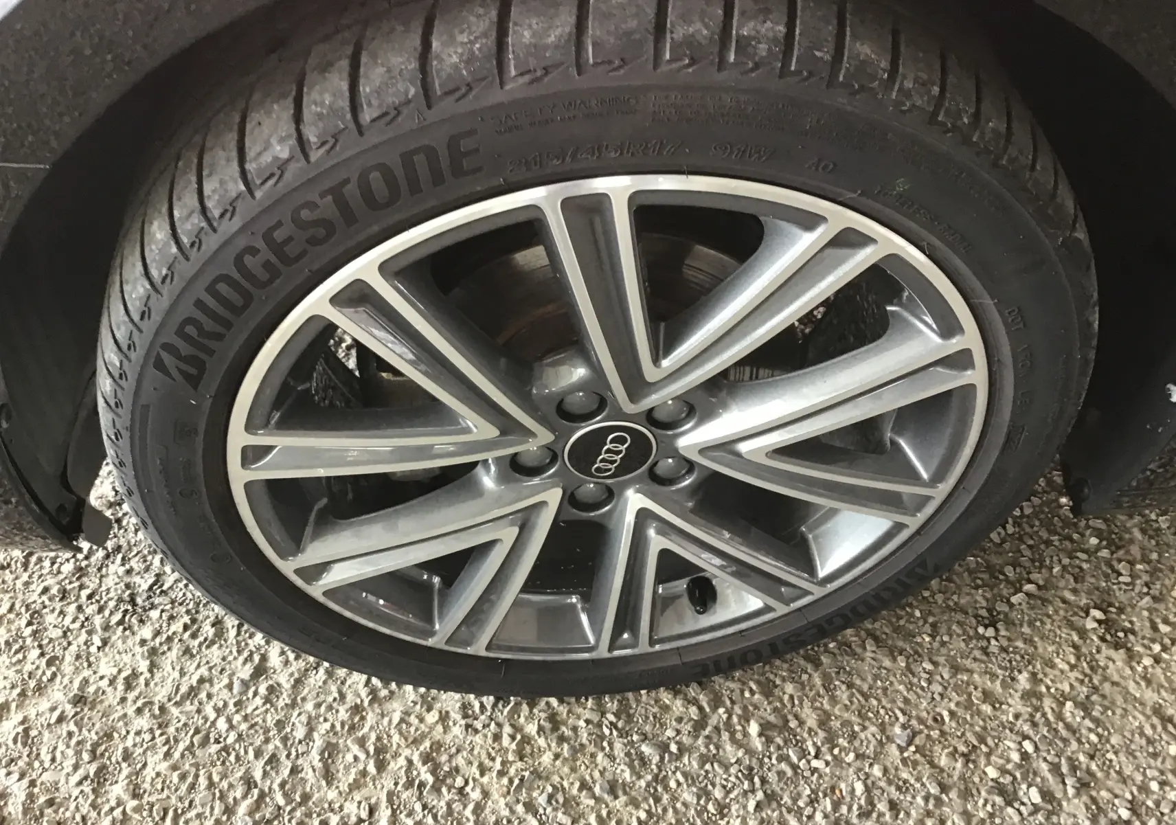 Gros plan sur la jante alliage 17 pouces gris et noir avec logo Audi au centre, montée sur pneu Bridgestone.
