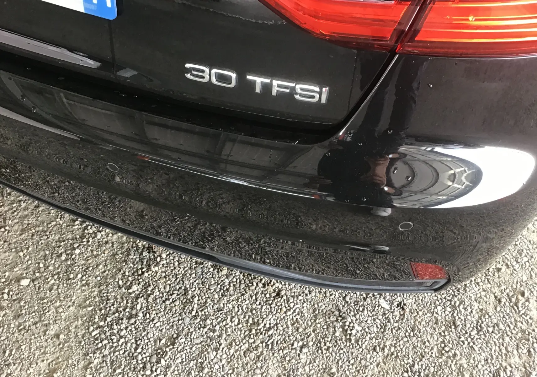 Gros plan sur le coffre arrière noir d’une Audi A1 Sportback 30 TFSI avec badge et feux arrière partiels visibles.