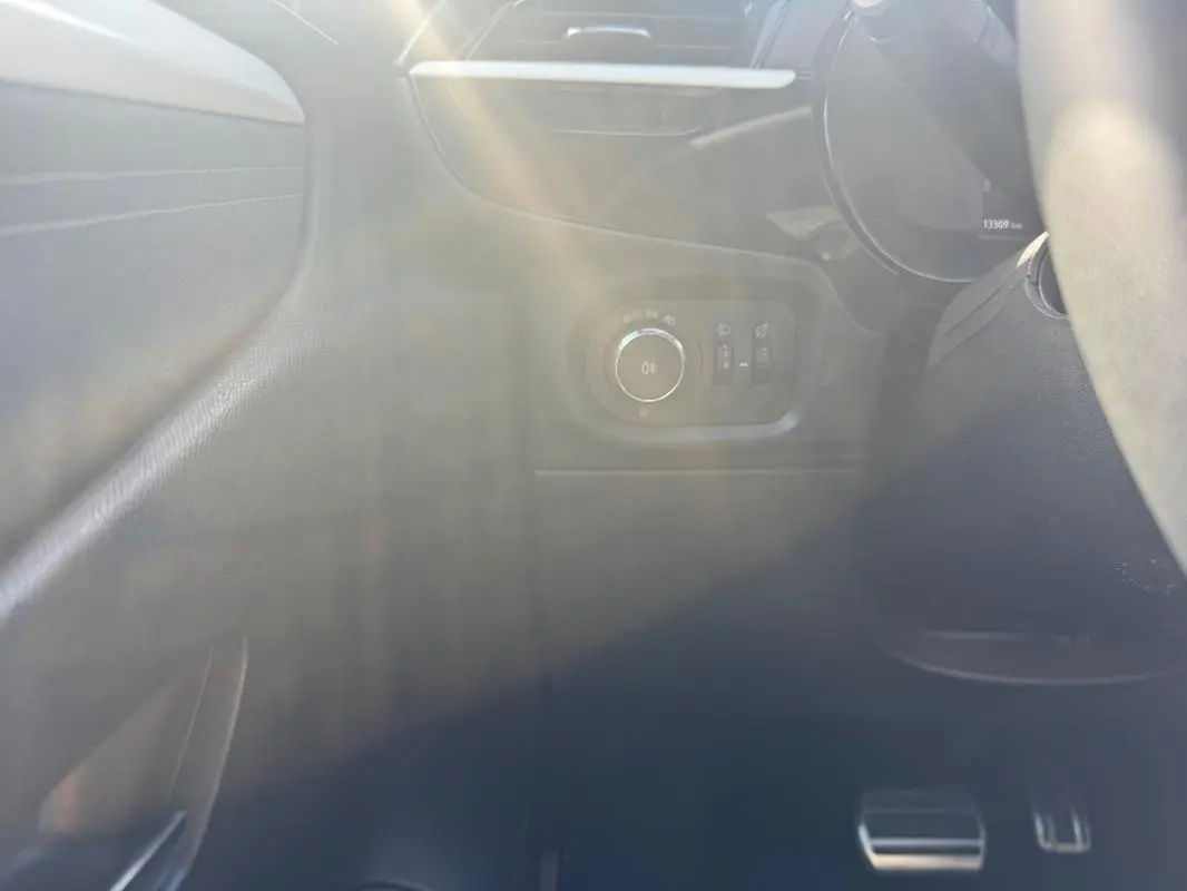 Détail du tableau de bord côté gauche de l’Opel Corsa noire 2025 avec commandes d’éclairage et pédales visibles.