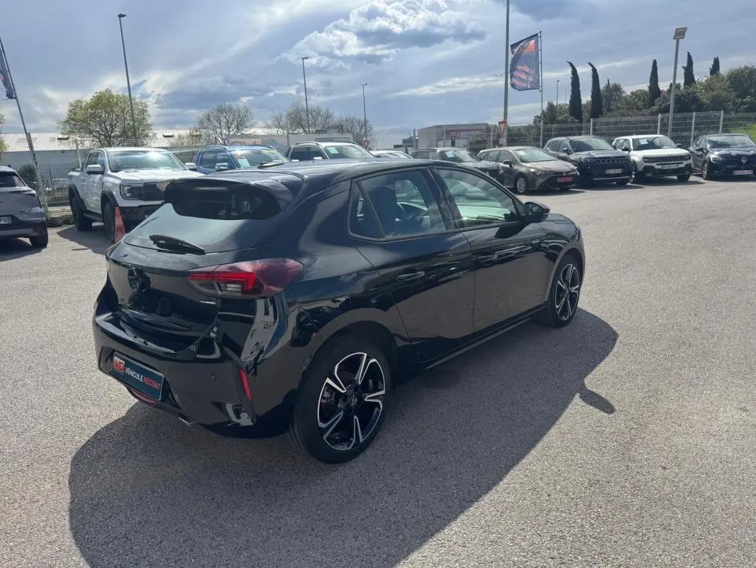 Opel Corsa noire vue 3/4 arrière droit, avec jantes alliage 17 pouces, stationnée en extérieur sous ciel nuageux.