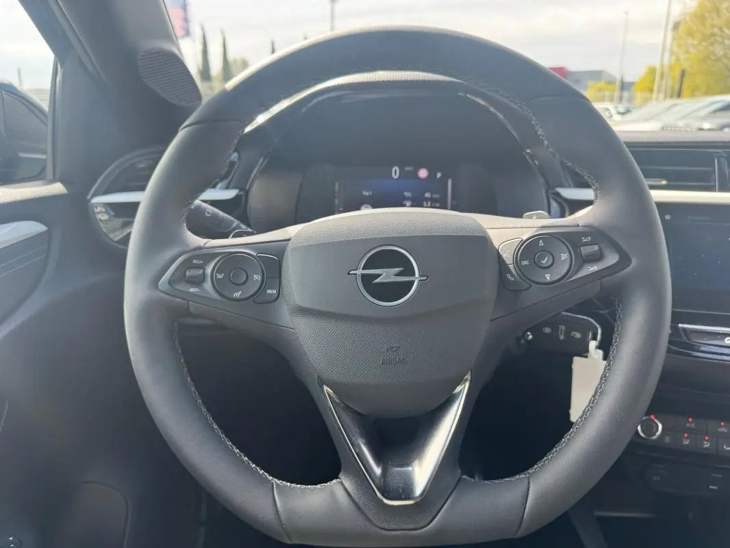 Vue rapprochée du volant noir multifonctions d’une Opel Corsa 2025 avec palettes au volant et tableau de bord numérique.