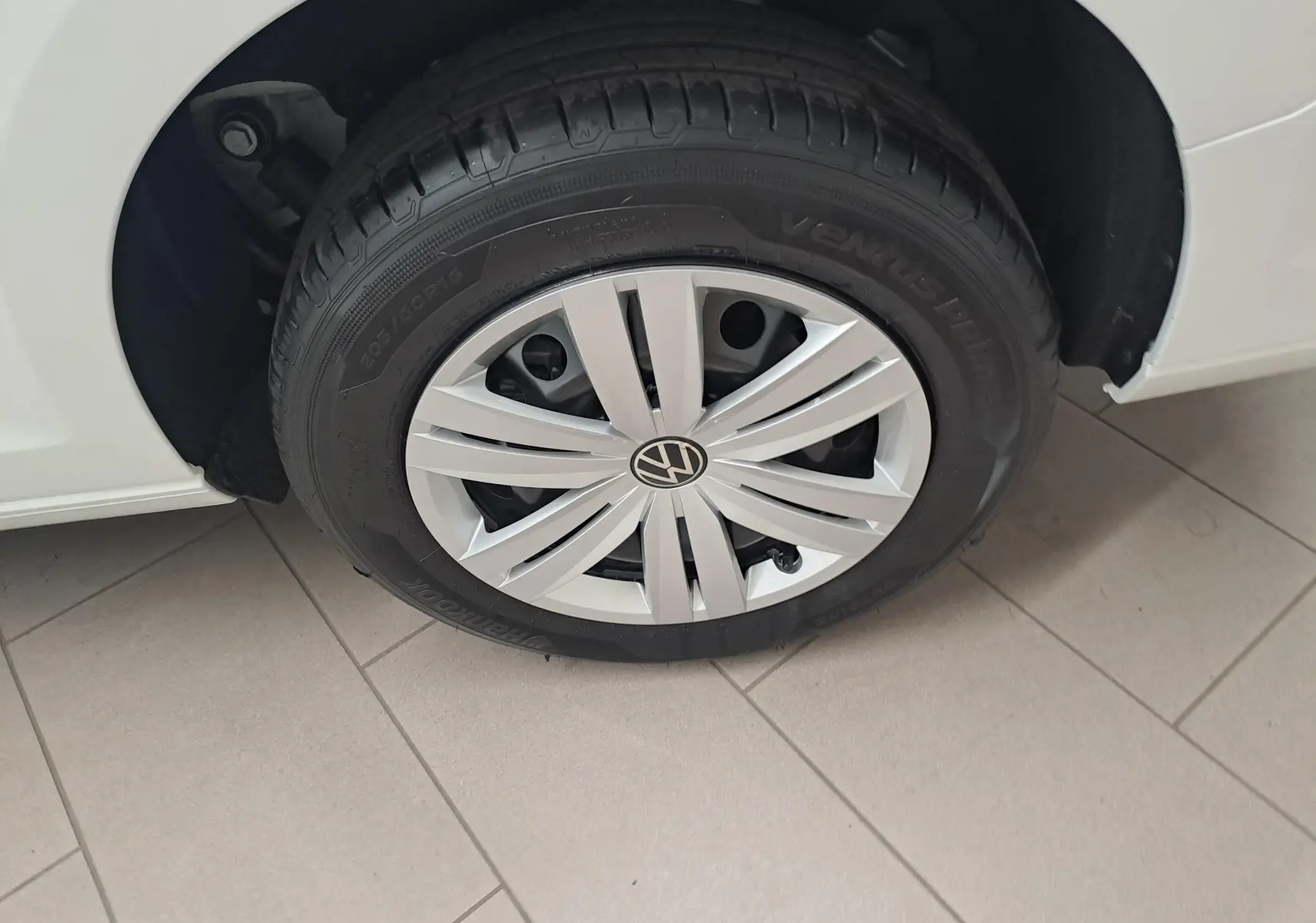 Gros plan sur la roue avant gauche du Volkswagen Caddy Cargo Maxi blanc candy, mettant en valeur la jante et le pneu.