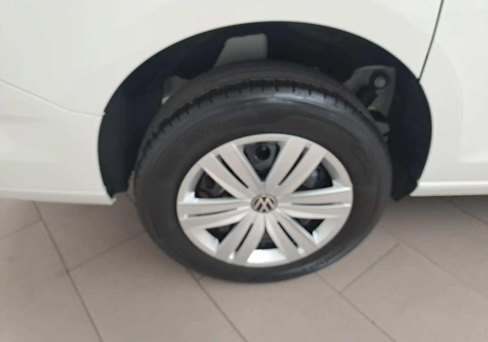 Gros plan sur la roue avant droite d’un Volkswagen Caddy Cargo Maxi blanc Candy, avec jante argentée et logo VW central.