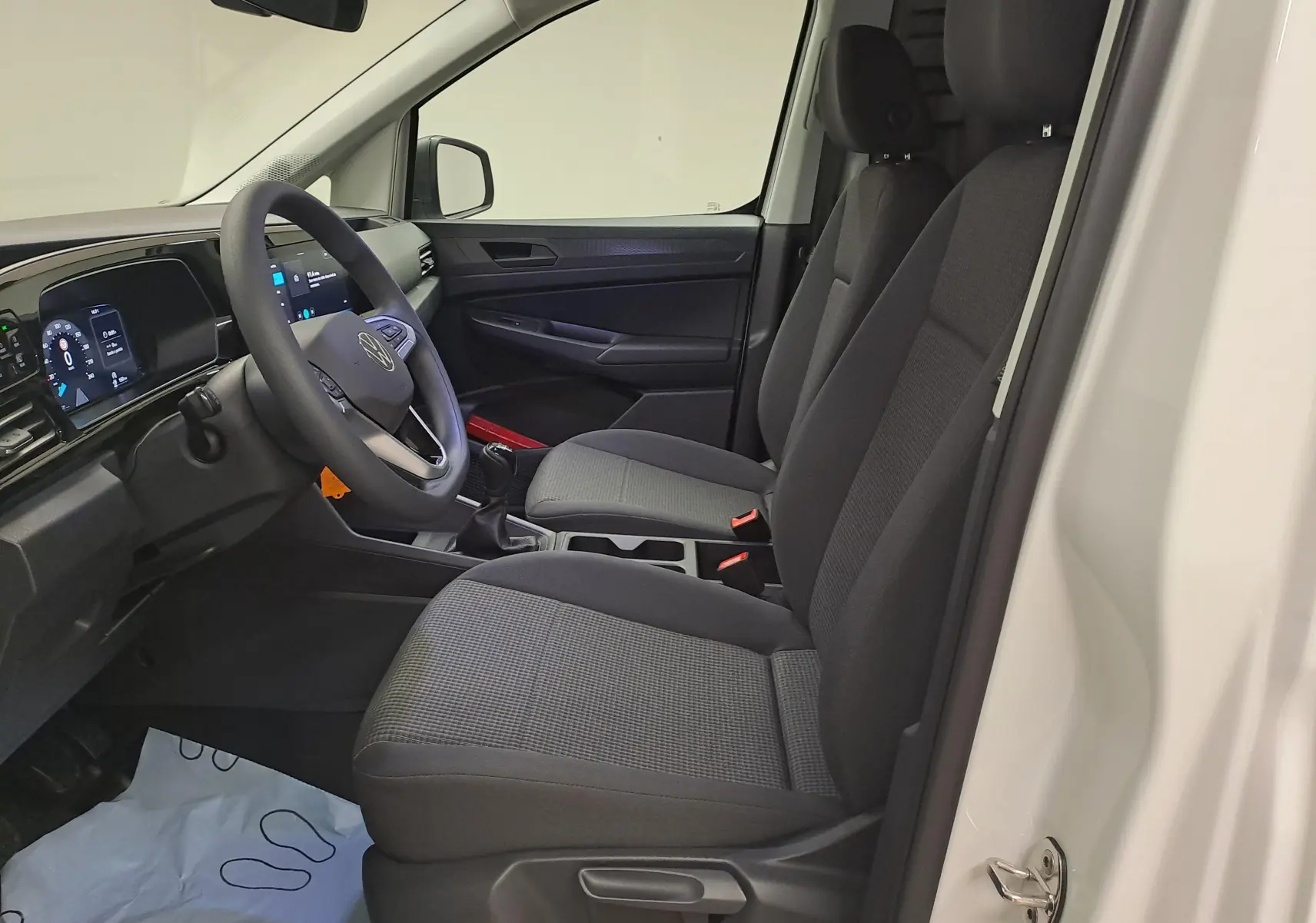 Intérieur côté conducteur du Volkswagen Caddy Cargo Maxi blanc, vue sur les sièges et le tableau de bord moderne.