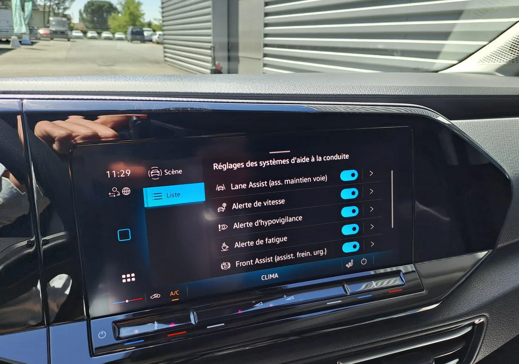 Vue rapprochée de l’écran tactile intérieur du Volkswagen Caddy Cargo Maxi blanc, affichant les réglages d’aide à la conduite.