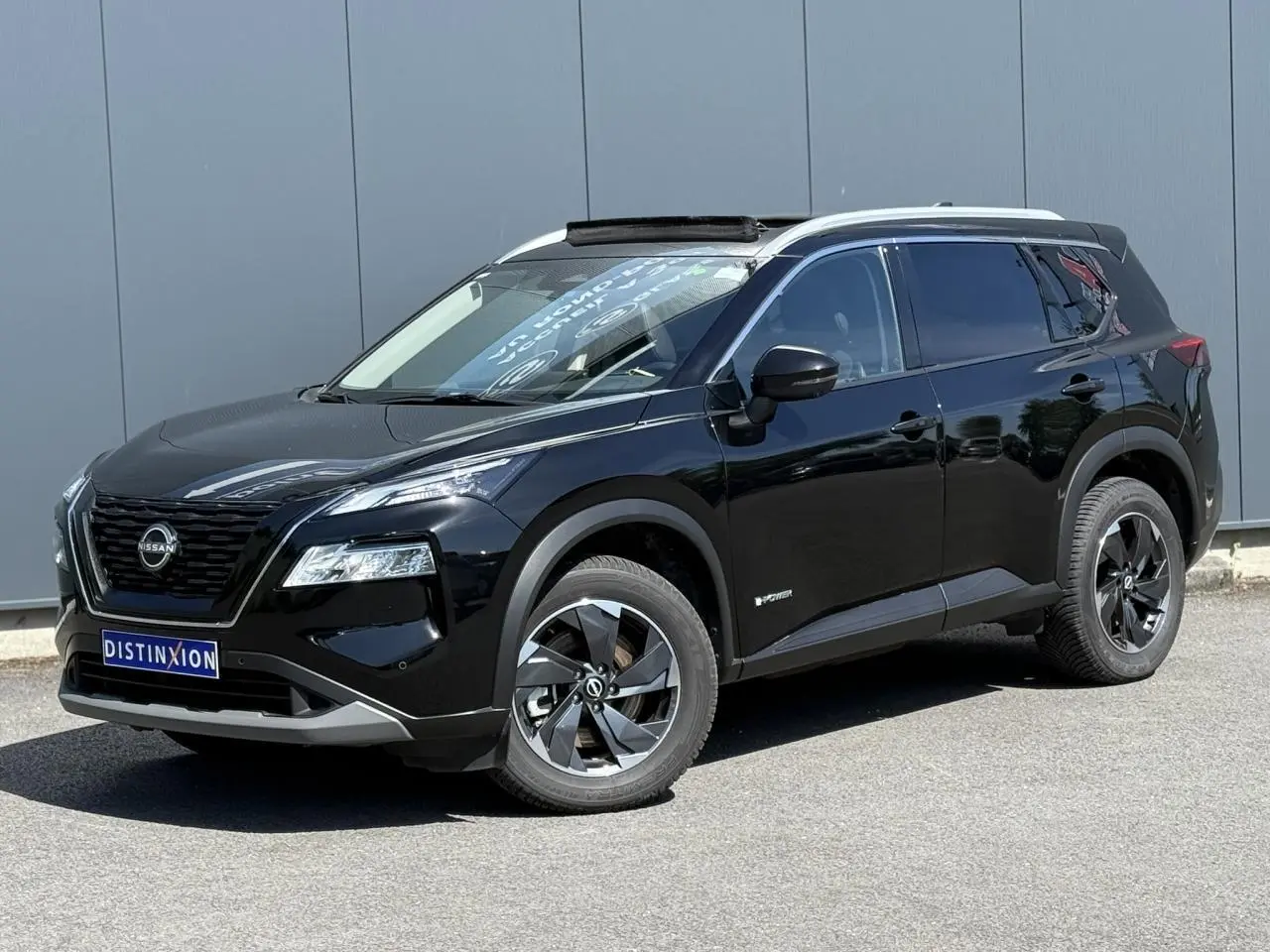 Nissan X-Trail 4x4 e-4orce noir intense en 3/4 avant droit avec toit panoramique ouvert.