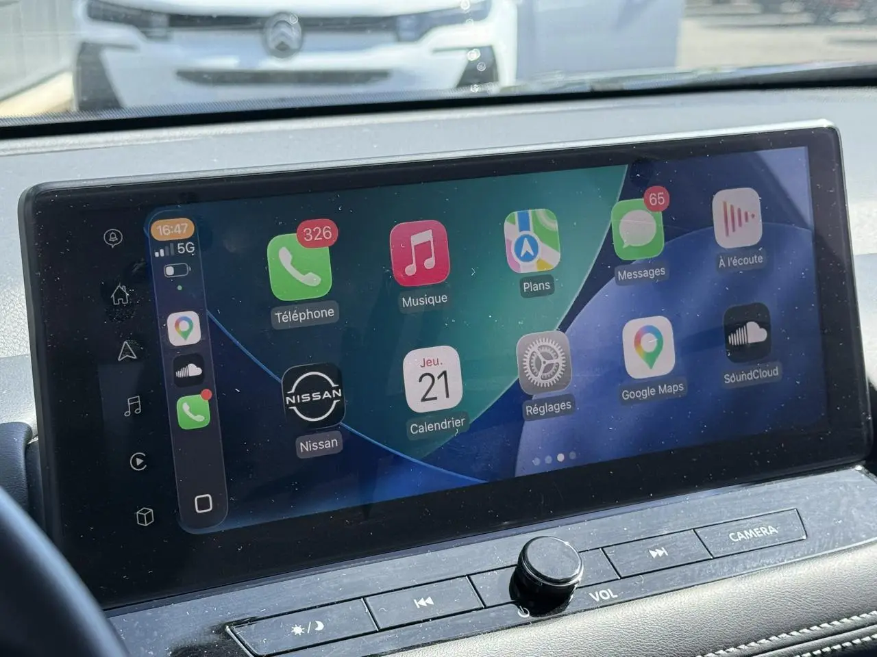 Écran tactile central du Nissan X-TRAIL 2024 affichant Apple CarPlay avec interface colorée et commandes intégrées.
