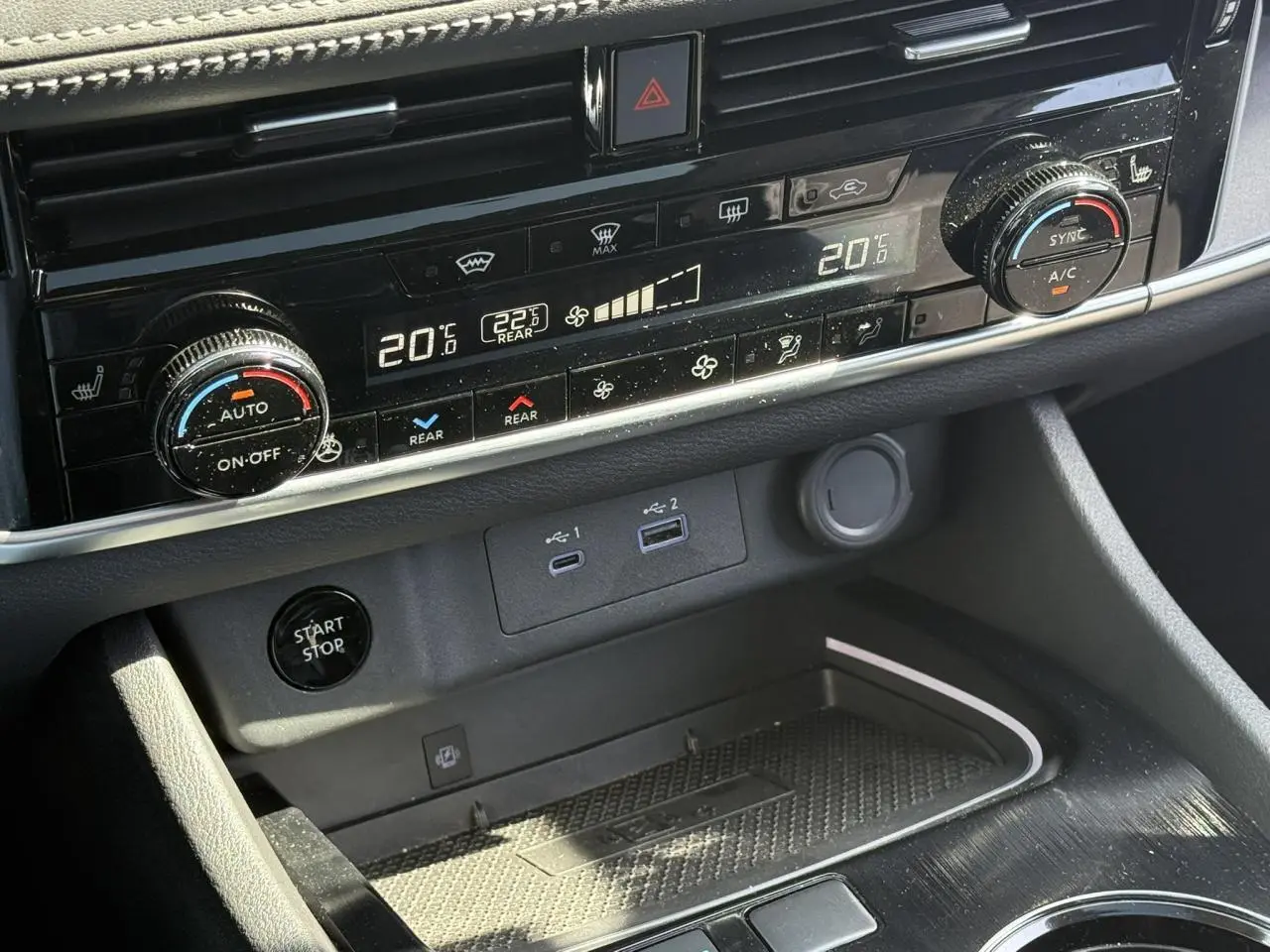 Vue rapprochée du tableau de bord noir du Nissan X-TRAIL 2024, montrant la climatisation automatique bi-zone et les ports USB.