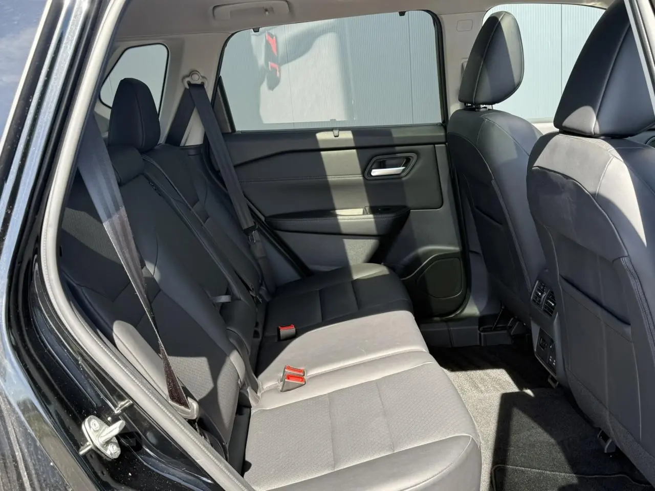 Vue intérieure côté gauche des sièges arrière en cuir noir du Nissan X-TRAIL 4X4 e-4orce 2024 avec ceinture de sécurité visible.