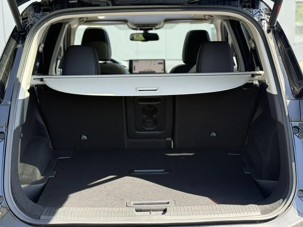 Coffre ouvert d’un Nissan X-TRAIL noir intense 2024, montrant l’espace de chargement avec cache-bagages déployé.