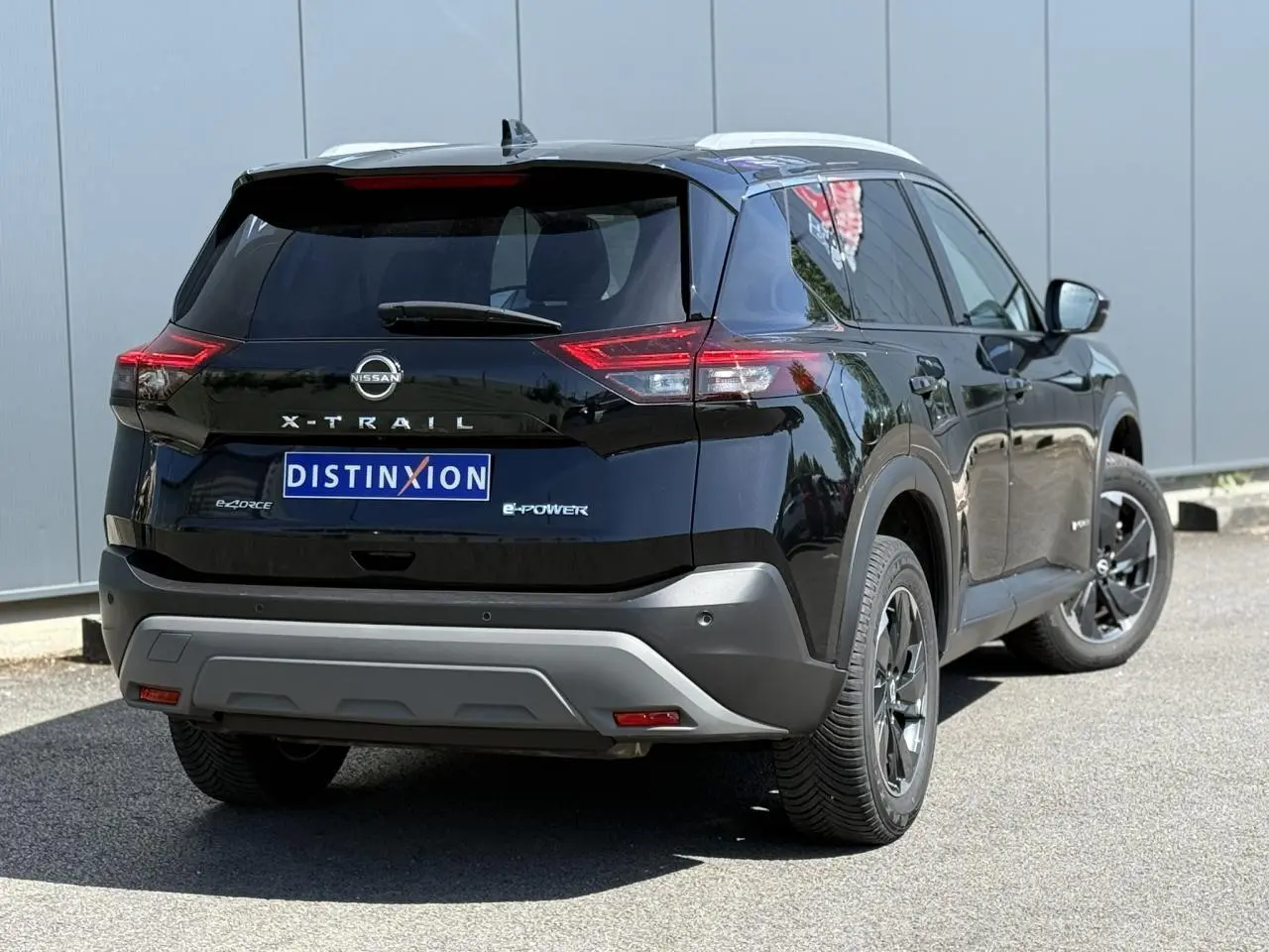 Vue 3/4 arrière droite du Nissan X-Trail 2024 noir intense avec badge e-4ORCE et toit panoramique visible.