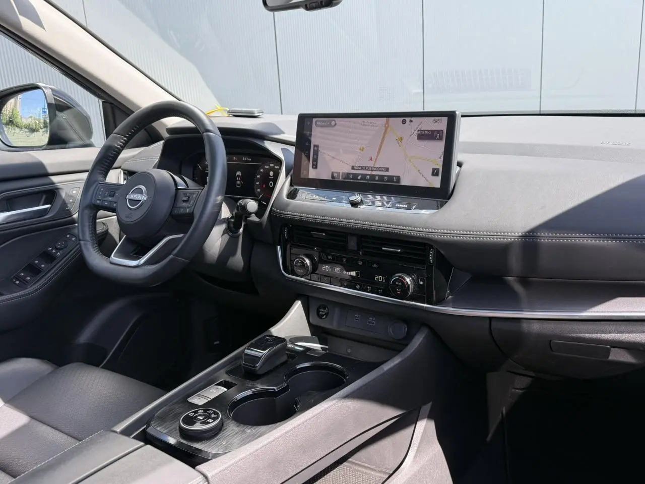 Vue intérieure côté conducteur du Nissan X-TRAIL 2024 noir intense, avec tableau de bord digital et écran tactile central.