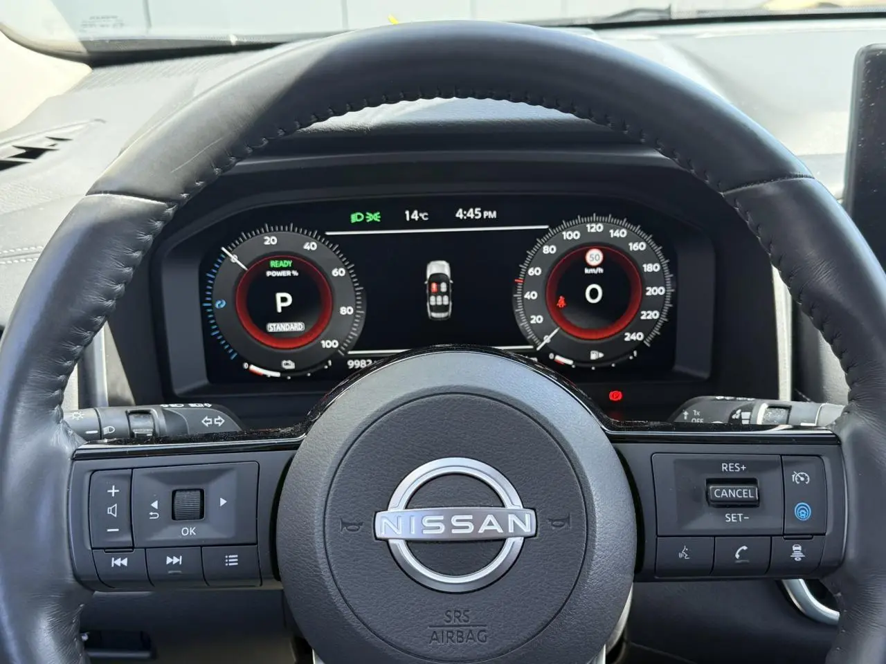 Vue intérieure centrée sur le volant cuir noir et le combiné d'instruments digital du Nissan X-TRAIL 2024.