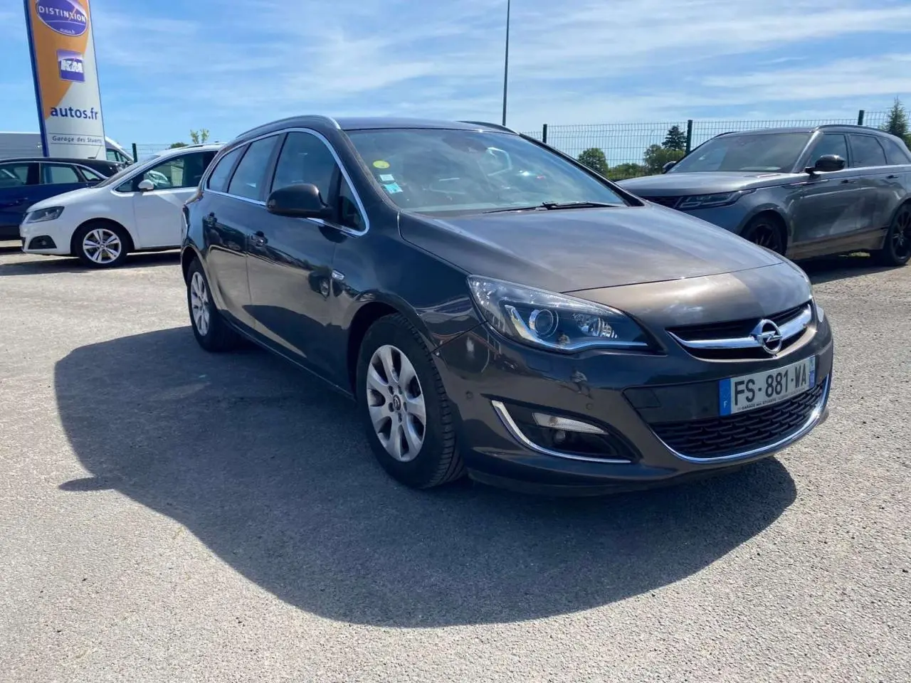 Opel Astra Sports Tourer gris vue 3/4 avant droit, phare LED et calandre chromée visibles, stationnée en extérieur.
