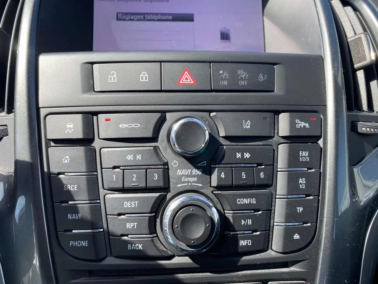 Gros plan sur la console centrale noire de l’Opel Astra Sports Tourer gris, montrant les boutons de navigation et commandes audio.