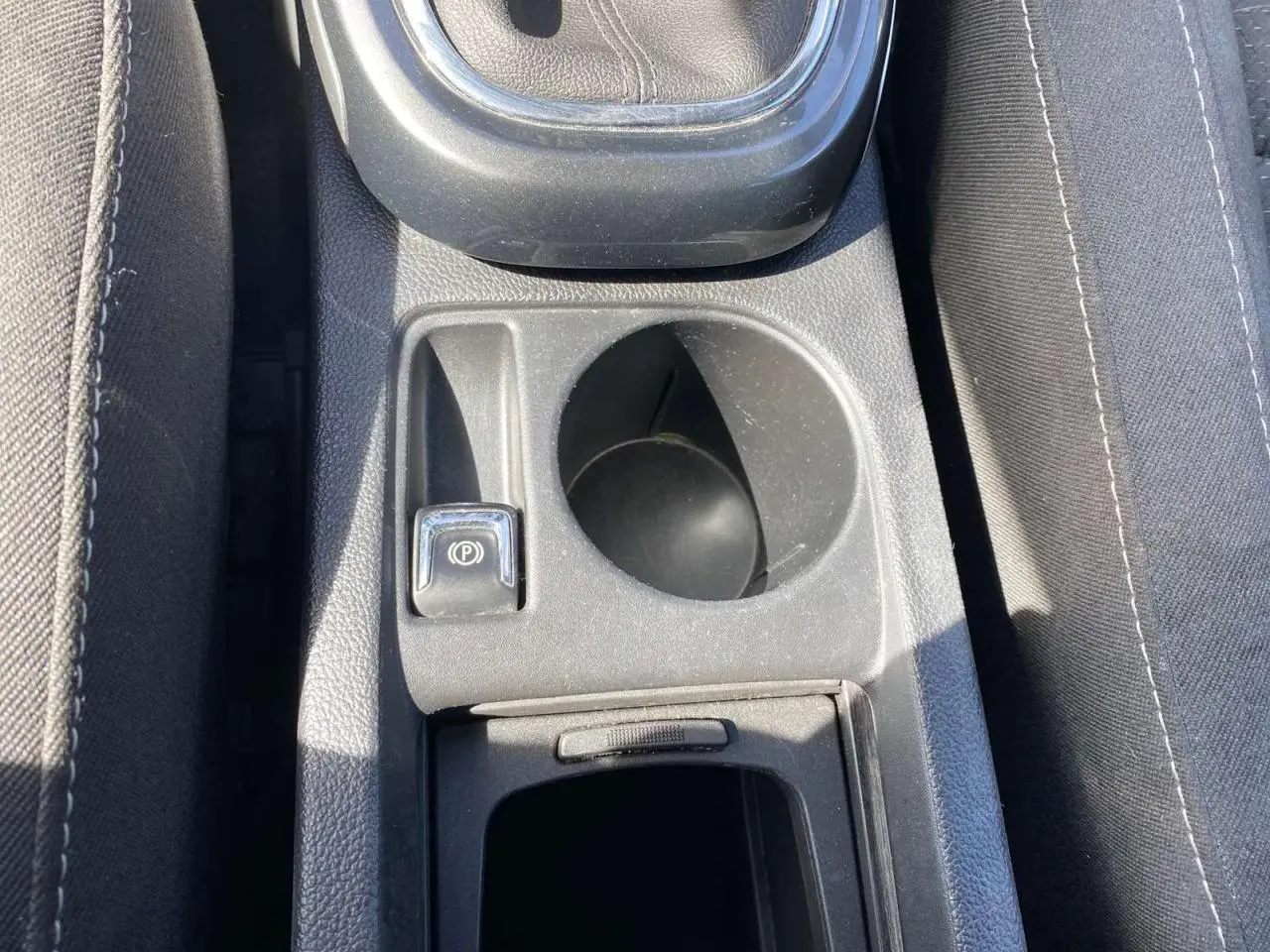 Gros plan sur la console centrale de l’Opel Astra Sports Tourer grise, montrant levier de vitesse, frein à main électrique et porte-gobelet.