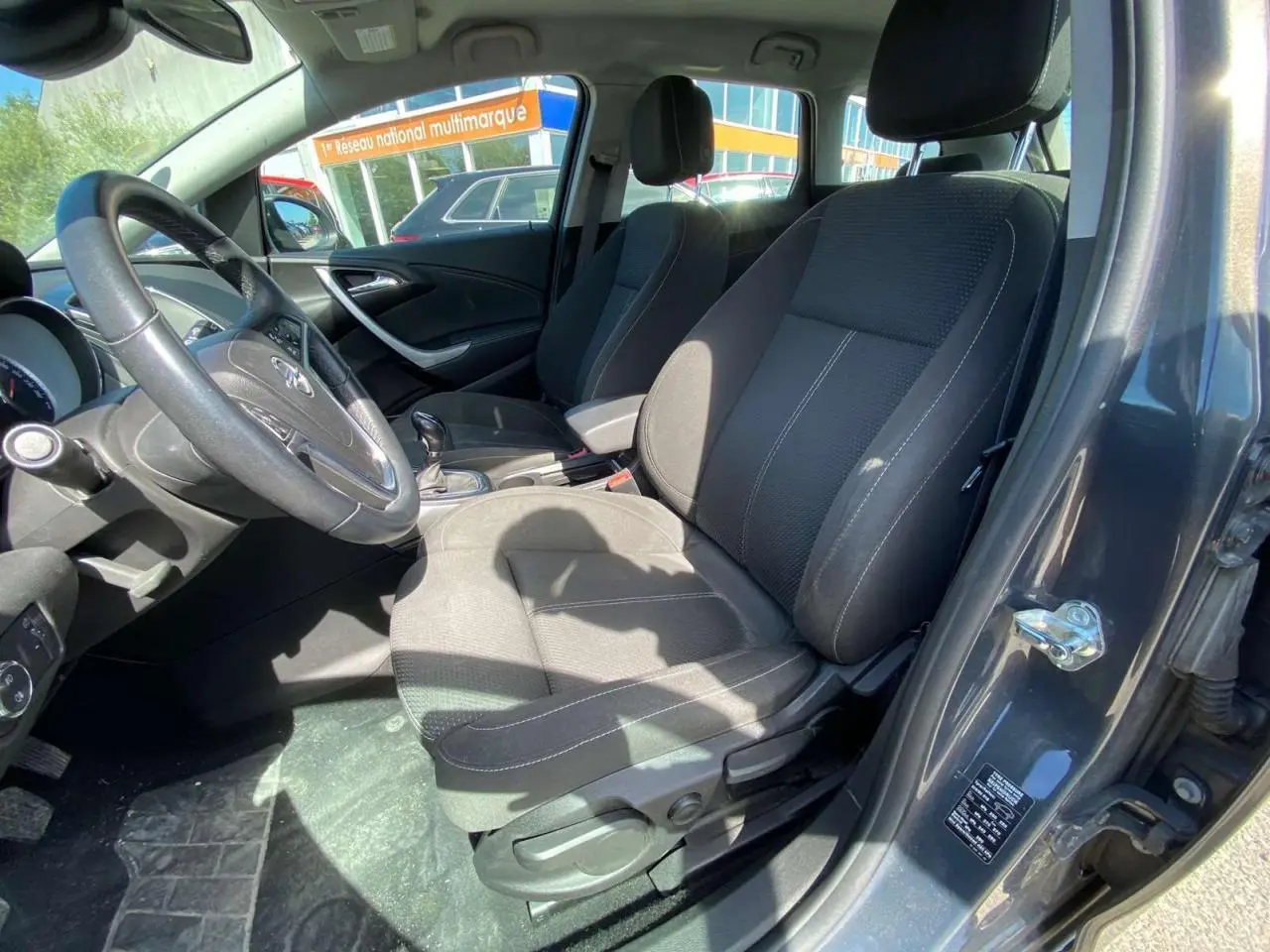 Vue intérieure côté conducteur de l’Opel Astra Sports Tourer gris, montrant les sièges et le volant en cuir.